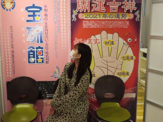 福岡占いの館「宝琉館」博多マルイ店で占い鑑定の待ち時間にパネルを見る女性